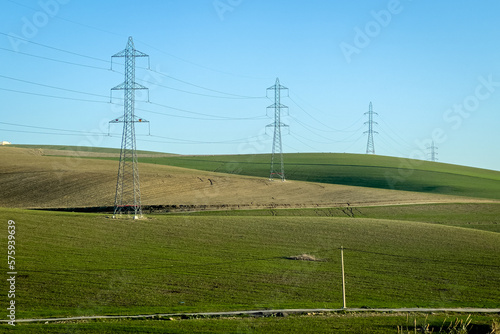 Electricity network poles on a rural area with a green field