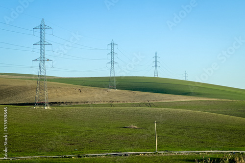 Electricity network poles on a rural area with a green field