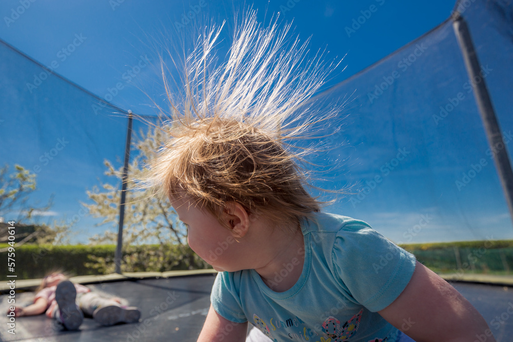 Electrified girl's hair whos jumping on a trampoline.