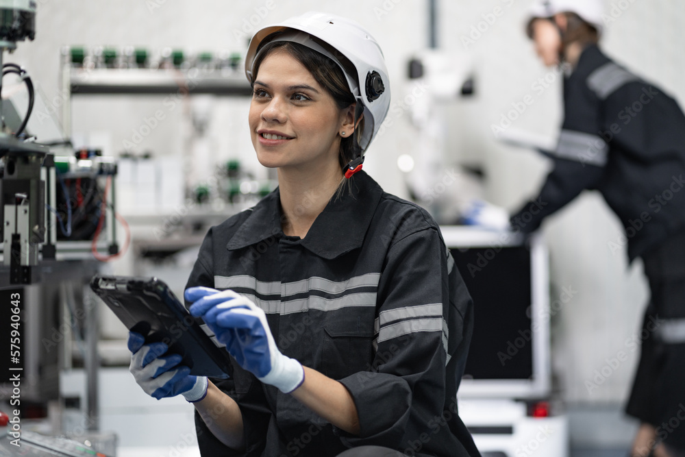 Engineer caucasian woman use tablet computer checking arm robot in the machine lap Engineer caucasian woman use tablet computer checking arm robot in the machine lap