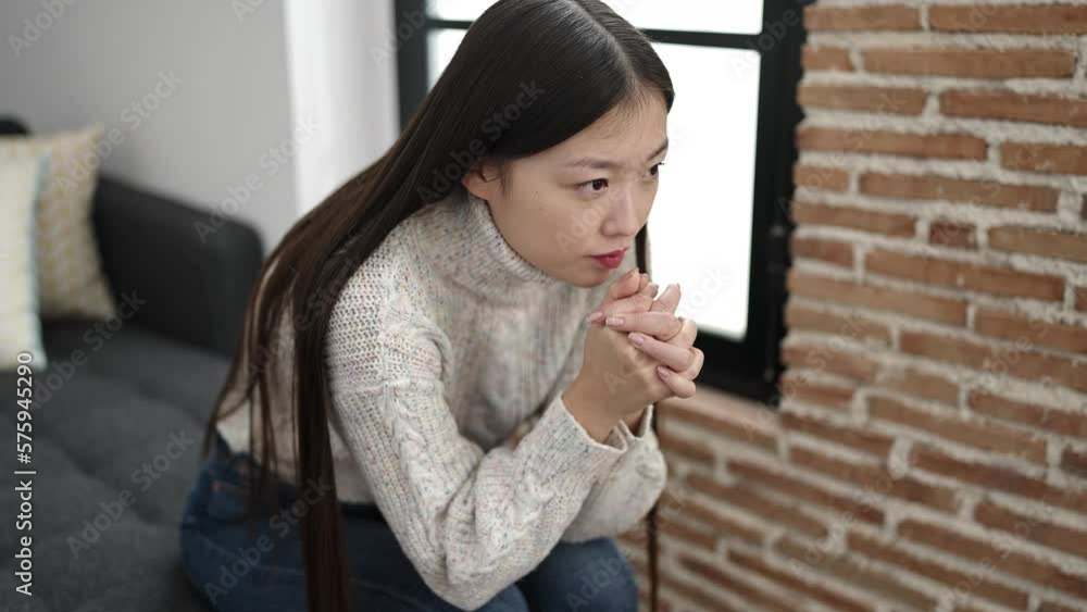 Young chinese woman sitting on sofa with serious expression at home Young chinese woman sitting on sofa with serious expression at home