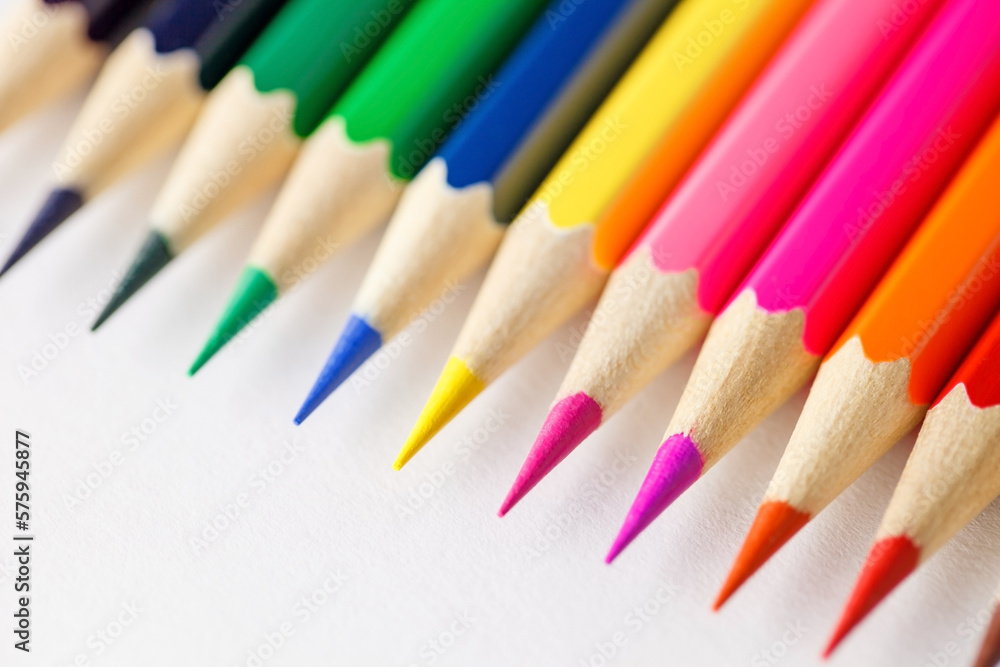 Colored pencils rainbow laid out side by side one to other on white background, rod writing material, close-up selective focus Colored pencils rainbow laid out side by side one to other on white background, rod writing material, close-up selective focus