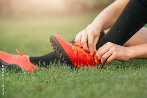 Football player tying shoelaces. The concept of preparation and safety of the game of football. Children's football club. Close-up of a football boot.