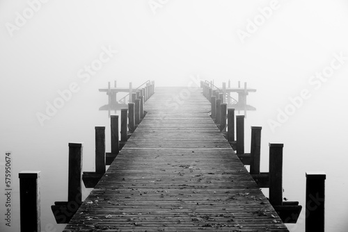 Jetty in the fog. Mystical foggy landscape at the lake. Morning fog in autumn. 