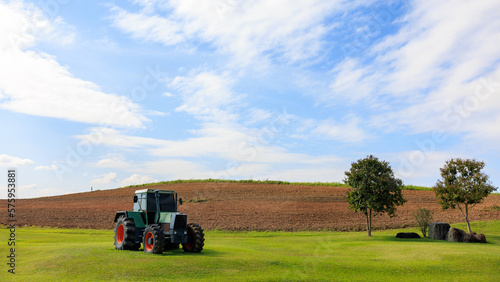 green tractor is parked in the middle of the farm.