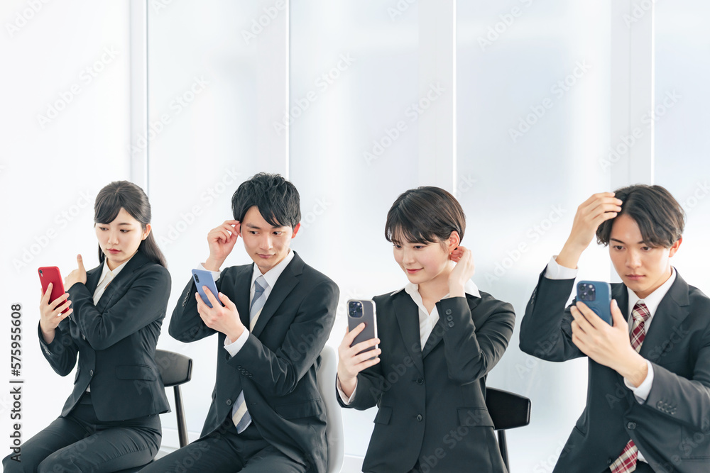 スマホを見て身だしなみを整える就活生のグループ
