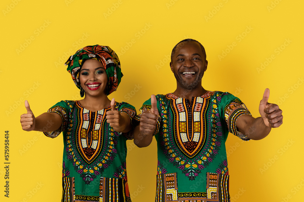 Obraz premium Cheery black man and woman in costumes showing thumb ups