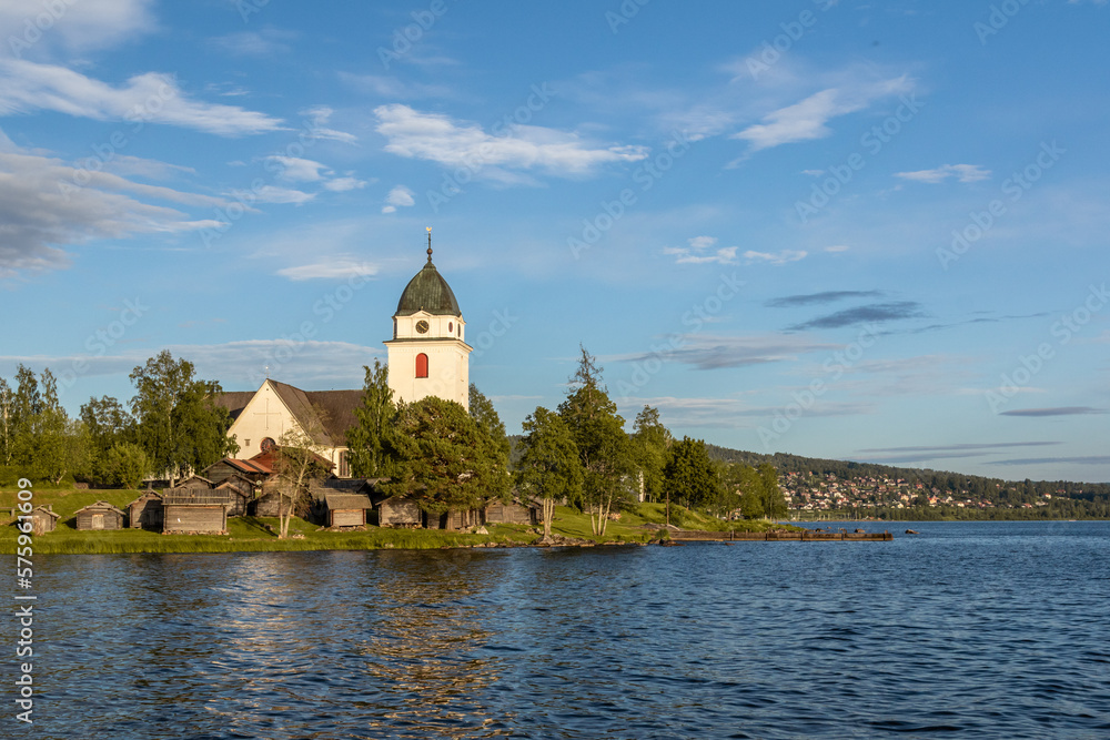 church and small wooden cabins on a lakeshore in the Swedish countryside