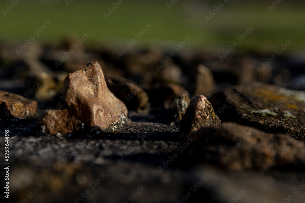 Small rocks found at the Roman defense wall remains embedded in concrete monument on historic archeologic outdoors site.