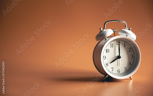 White alarm clock on brown background isolated.