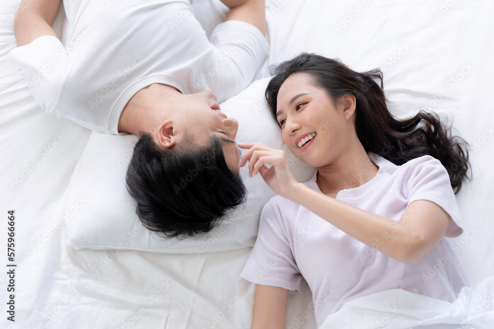 Happy Asian couple lying down smiling and relaxing together in bed. Happy Asian couple lying down smiling and relaxing together in bed.