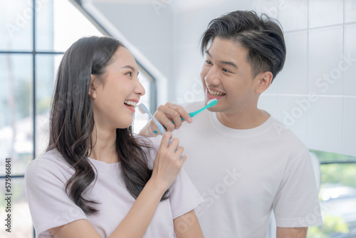 Happy Asian couple brushing their teeth together in the bathroom.