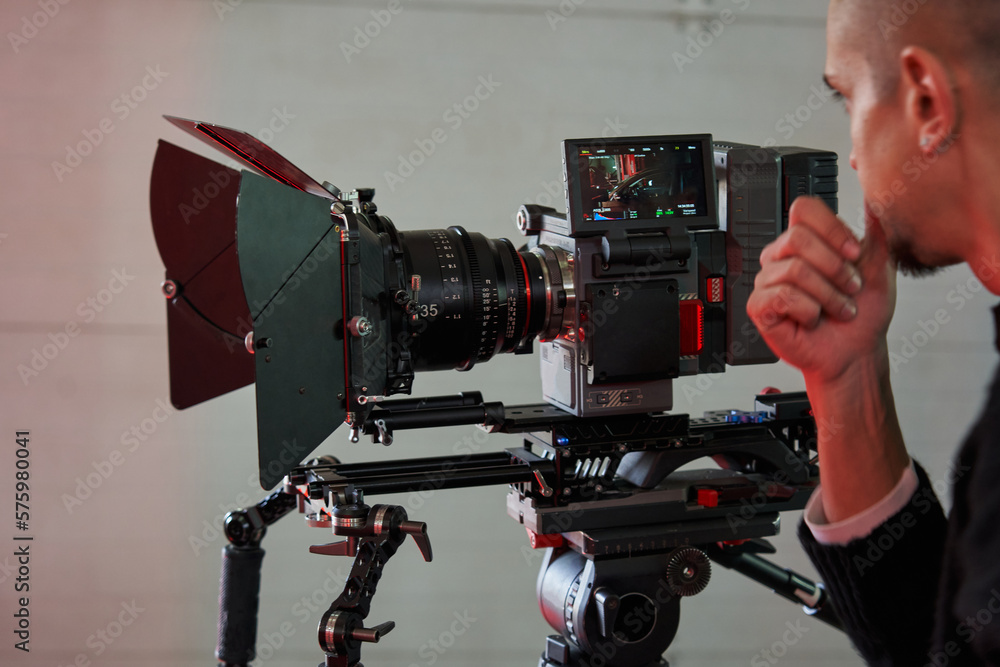 caucasian man cameraman carefully looks at the screen of a professional ...