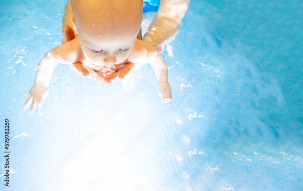 Adorable baby girl enjoying swimming in a pool with her mother early