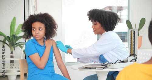 Foto African-American children getting vaccine in clinic or hospital, with hand nurse injecting vaccine to get immunity for protection