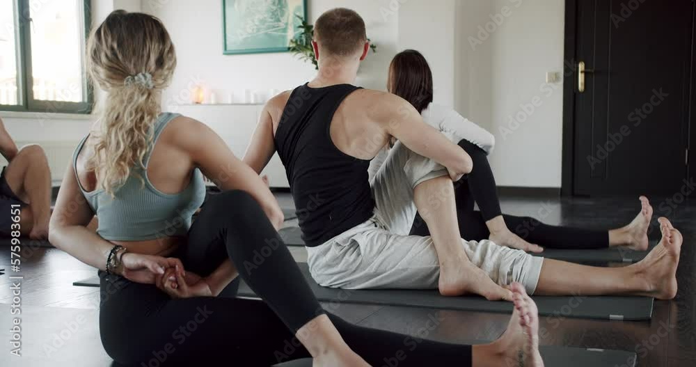 Young sporty attractive people practicing yoga lesson with instructor. Men and women stretching in studio together. exercising healthy lifestyle in fitness studio. Sport activity, Yoga class indoors. Young sporty attractive people practicing yoga lesson with instructor. Men and women stretching in studio together. exercising healthy lifestyle in fitness studio. Sport activity, Yoga class indoors.