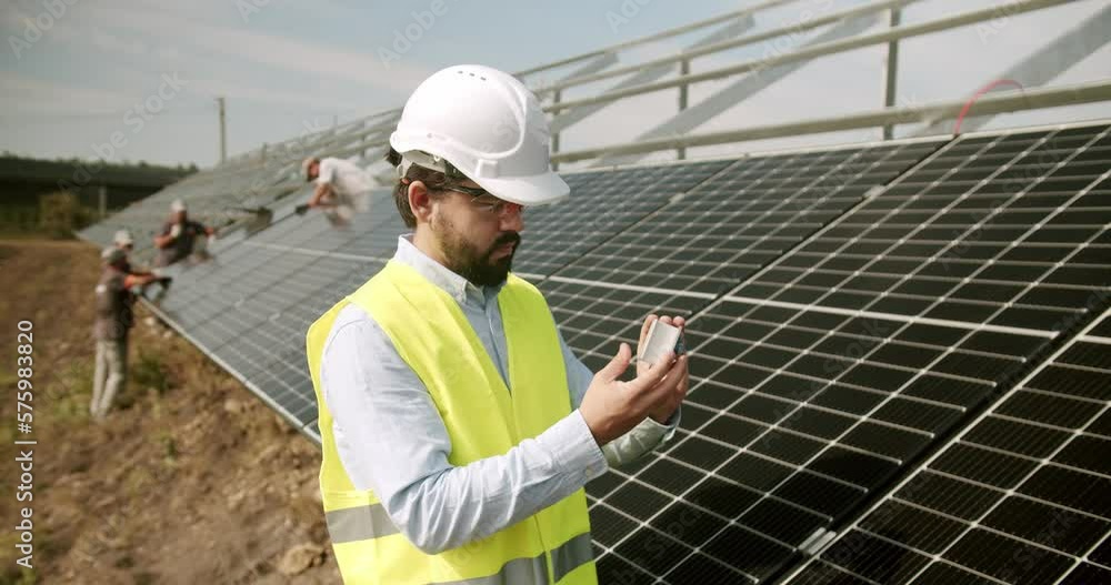 Technician installing solar panels on metal stand. Technician connecting solar panel. Technician working with electrical screwdriver installing solar panel to metal platform system.