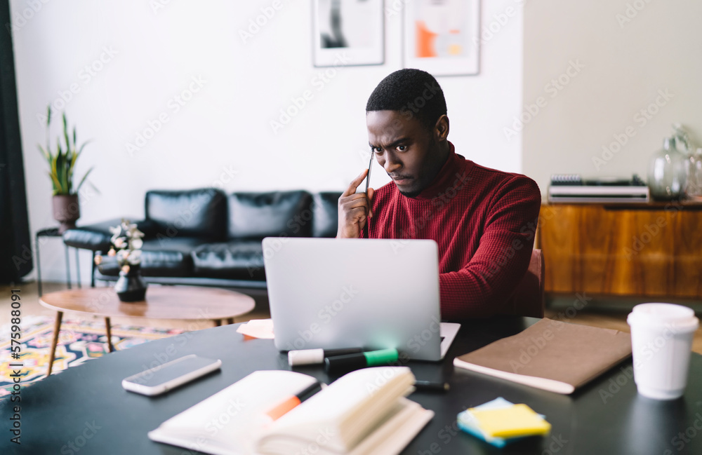 Focused black man using laptop in office Focused black man using laptop in office