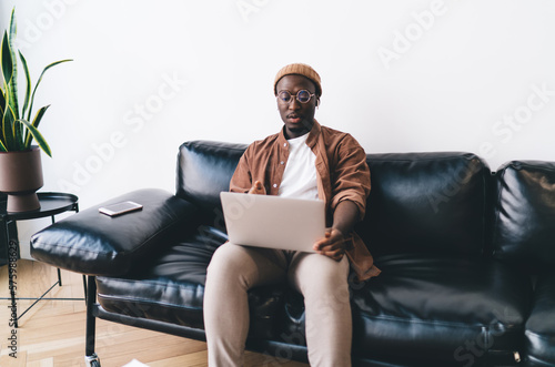 Stylish ethnic freelancer working on sofa © BullRun