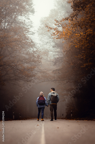 Couple spending time together walking on forest road on a foggy morning.