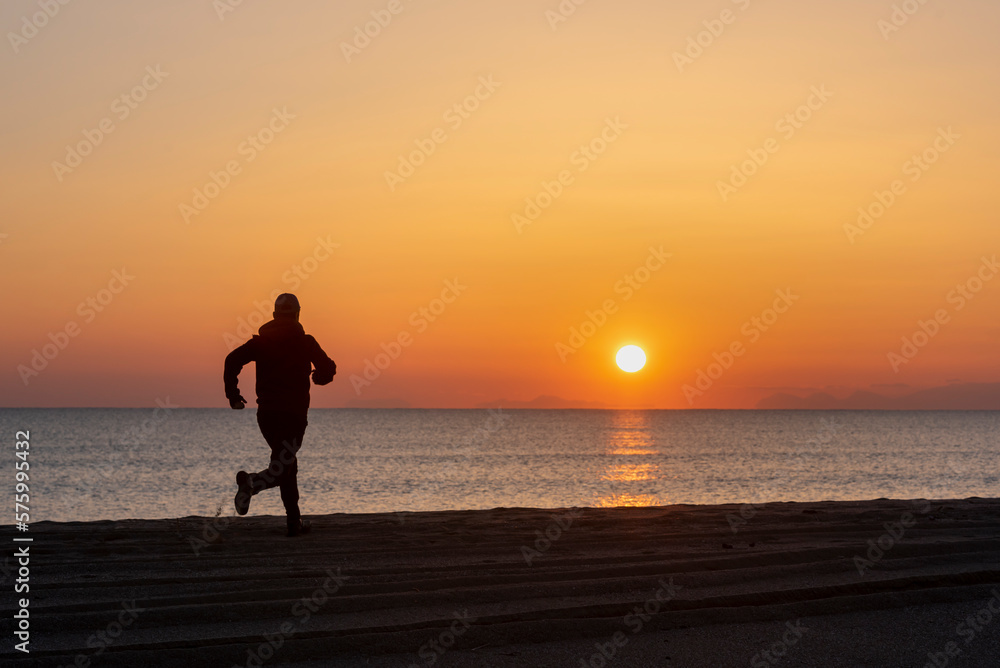 silhouette of a man running on the beach at sunset