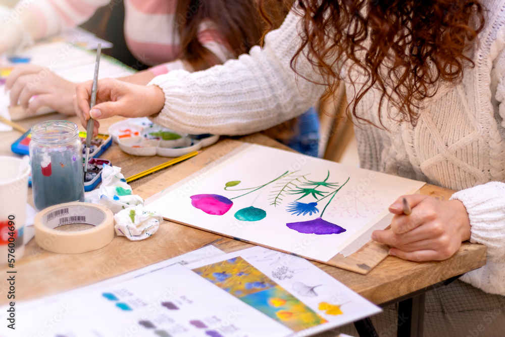 Fototapeta premium Watercolor Painting Workshop. Pretty female artist in the art studio and painting on paper.
