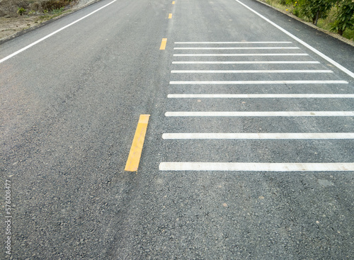 The white transverse rumble strips on the asphalt road.