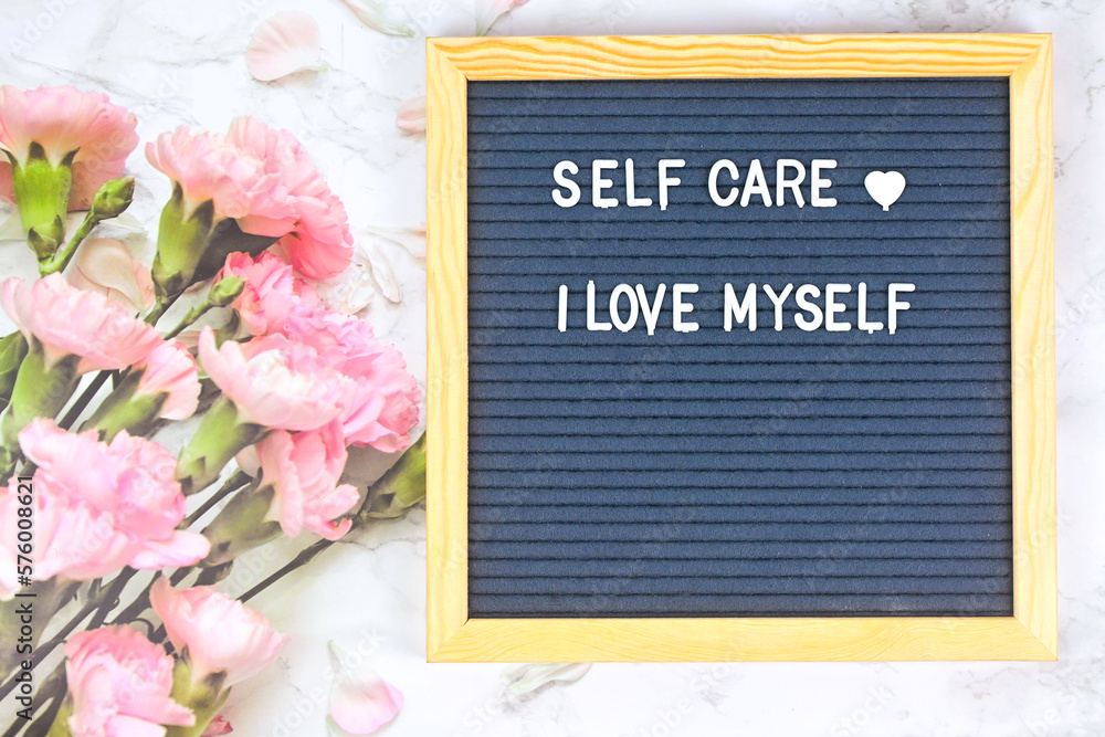 Grey letter board with phrase Self care, I am loved. Self love
