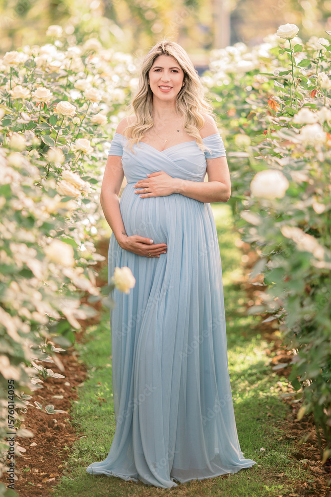 Barriga da mamãe grávida com vestido azul, a espera do bebê, entre plantação de flores no campo na primavera. Barriga da mamãe grávida com vestido azul, a espera do bebê, entre plantação de flores no campo na primavera.