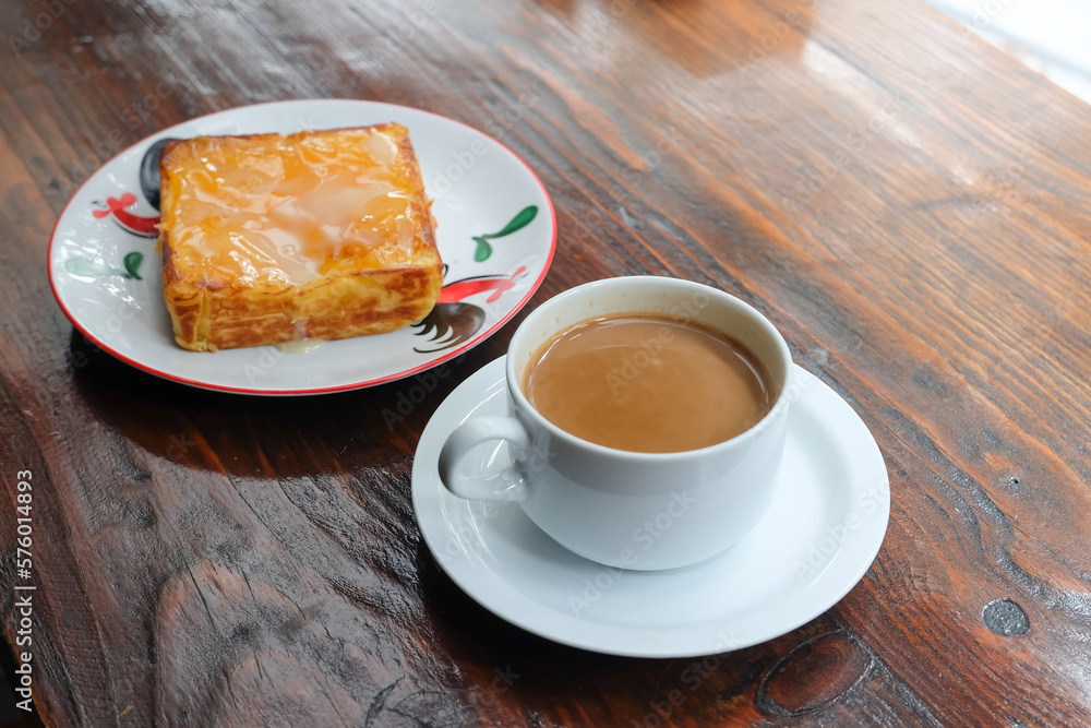 cup of coffee and toasted bread on the wooden table with a garden view cup of coffee and toasted bread on the wooden table with a garden view