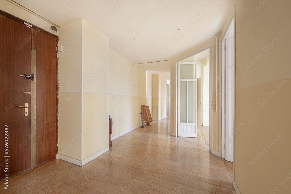 Spacious entrance hall of a house with a wooden access door with golden security hinges, vintage white woodwork and parima pine wood floors Spacious entrance hall of a house with a wooden access door with golden security hinges, vintage white woodwork and parima pine wood floors