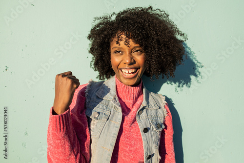 Happy young woman cheering in front of green wall photo