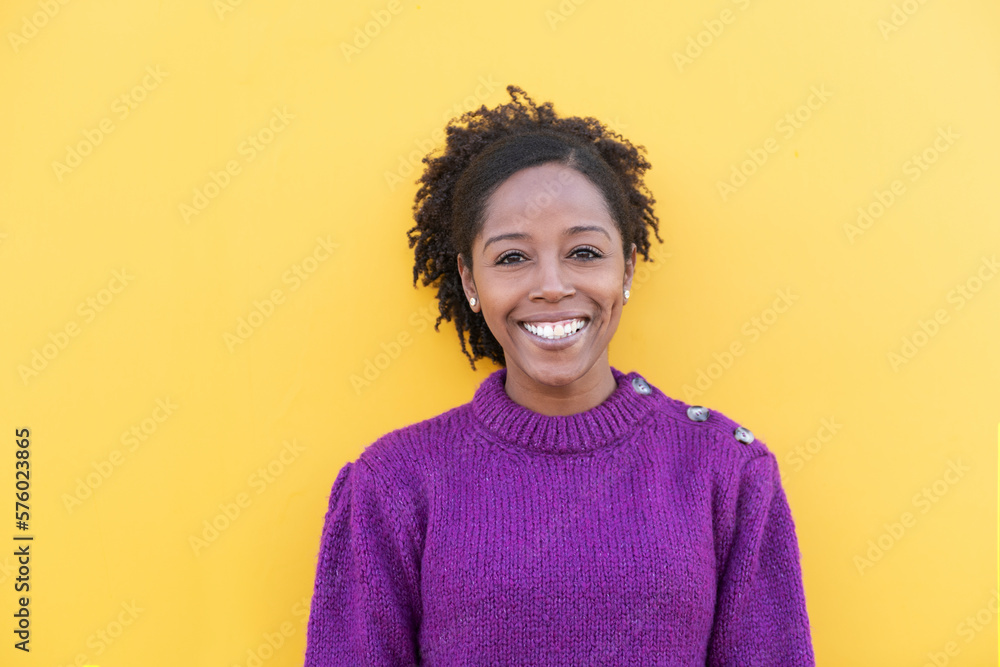 Happy woman standing in front of yellow wall Happy woman standing in front of yellow wall