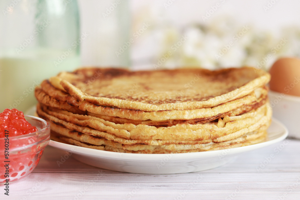 Stack of freshly baked pancakes lie in white plate. Pancake week. Selective focus. Glass bottle with milk, crepes, caviar and egg Stack of freshly baked pancakes lie in white plate. Pancake week. Selective focus. Glass bottle with milk, crepes, caviar and egg