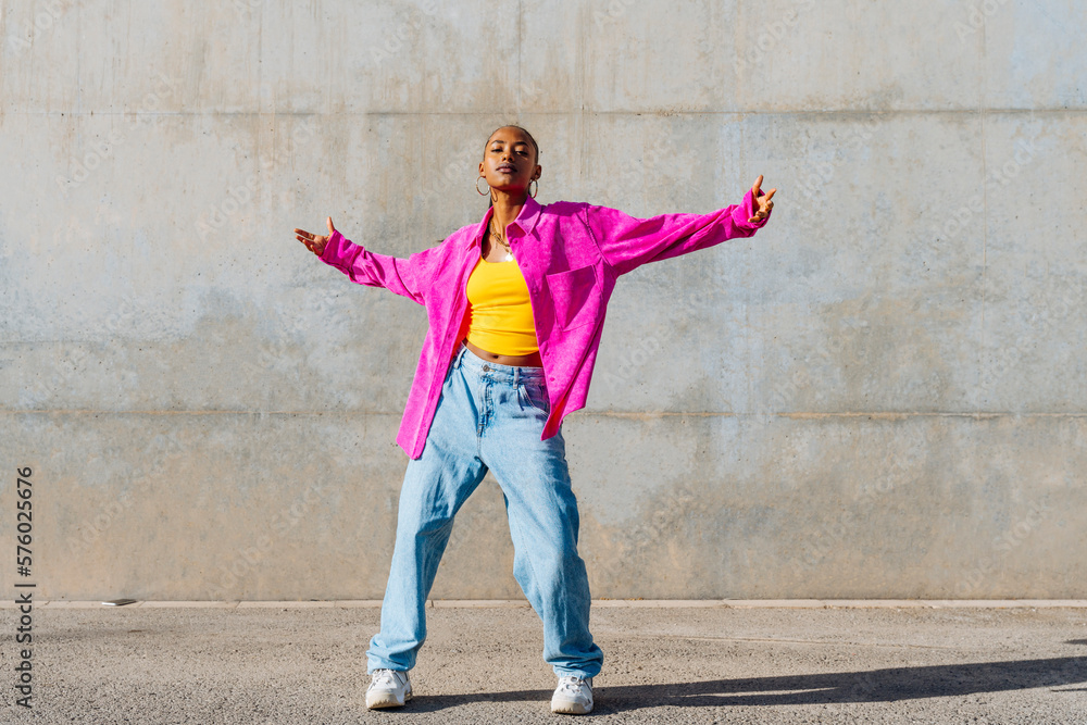 Young dancer with arms outstretched in front of wall Young dancer with arms outstretched in front of wall
