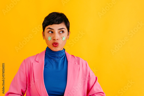 Young woman puckering with stickers on face against yellow background photo