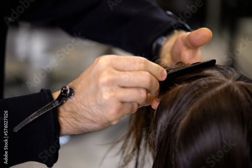 male hairdresser is combing the hair of the female client.