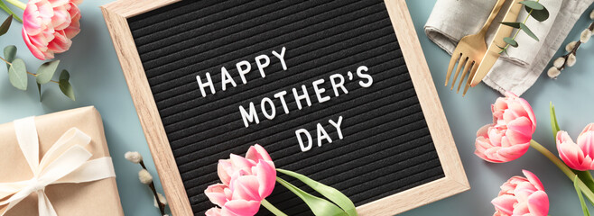 Spring season still life with pink tulips and Happy Mother's day text on letter board top view