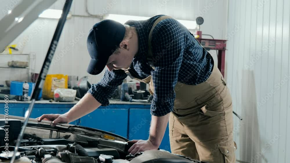 An auto mechanic inspects a car for damage. A mechanic diagnoses a car engine. Old car repair An auto mechanic inspects a car for damage. A mechanic diagnoses a car engine. Old car repair