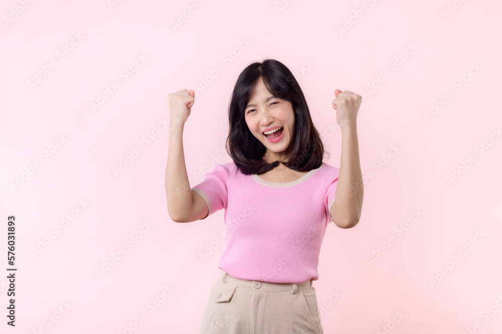 Portrait beautiful young asian woman happy smile with fist up victory gesture expression cheerful her success achievement against pink pastel studio background. Woman day winner celebration concept. Portrait beautiful young asian woman happy smile with fist up victory gesture expression cheerful her success achievement against pink pastel studio background. Woman day winner celebration concept.