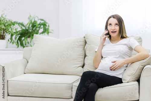 Pregnant woman sharing secrets and talking over the phone.