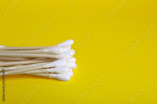 Wooden cotton buds on yellow background. Space for text