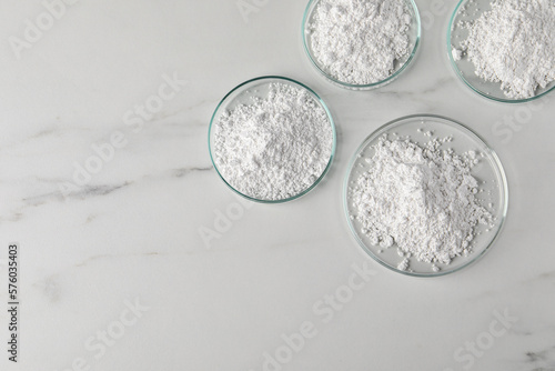 Canvastavla Many petri dishes with calcium carbonate powder on white marble table, flat lay