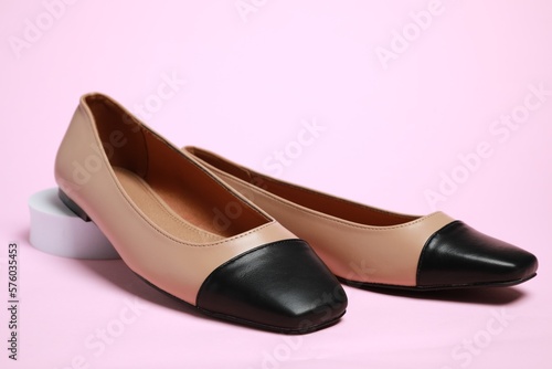 Pair of new stylish square toe ballet flats on pale pink background
