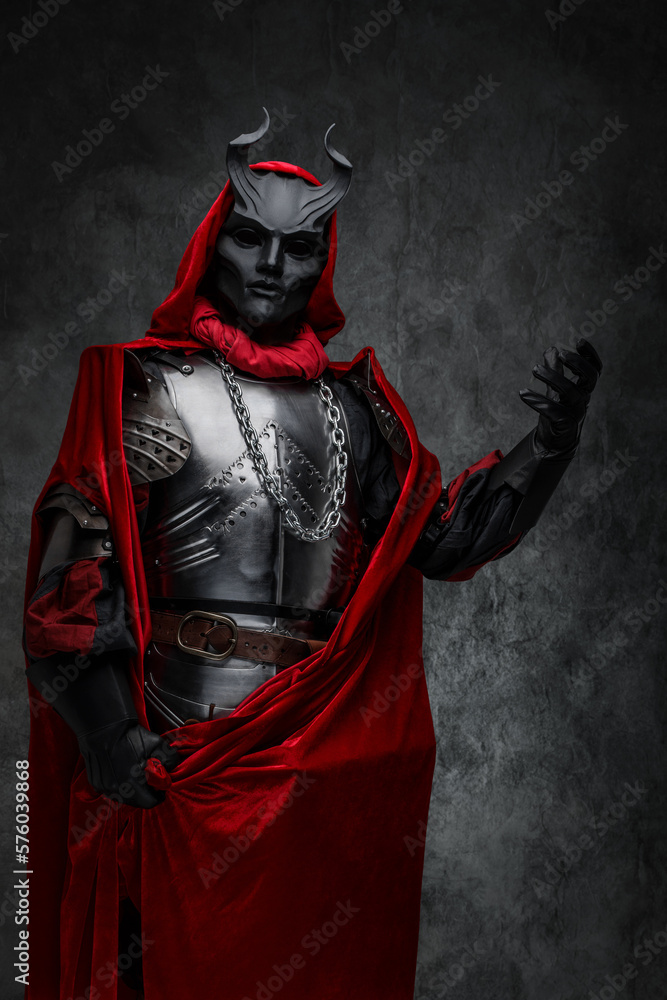 Studio shot of mystic prayer of dark cult dressed in silver plate armor and horned mask. Studio shot of mystic prayer of dark cult dressed in silver plate armor and horned mask.