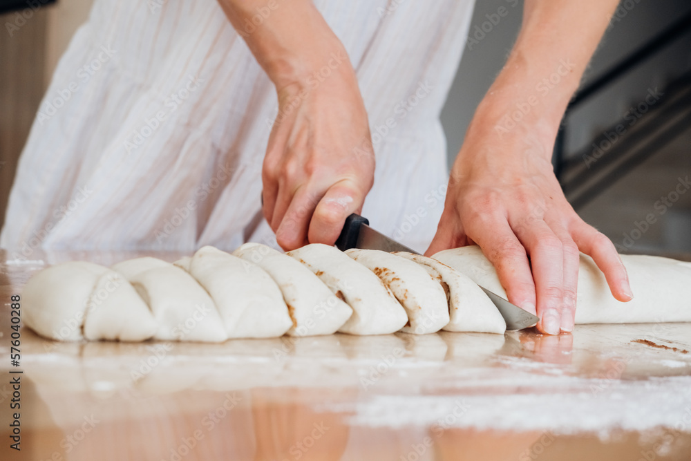 Close up of young woman cutting dough for homemade bakery.