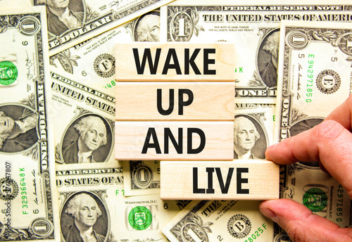 Wake up and live symbol. Concept words Wake up and live on wooden blocks. Beautiful background from dollar bills. Businessman hand. Business lifestyle wake up and live concept. Copy space.