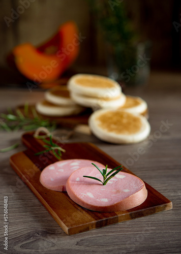 slices of Bologna PGI mortadella on wooden cutting board photo