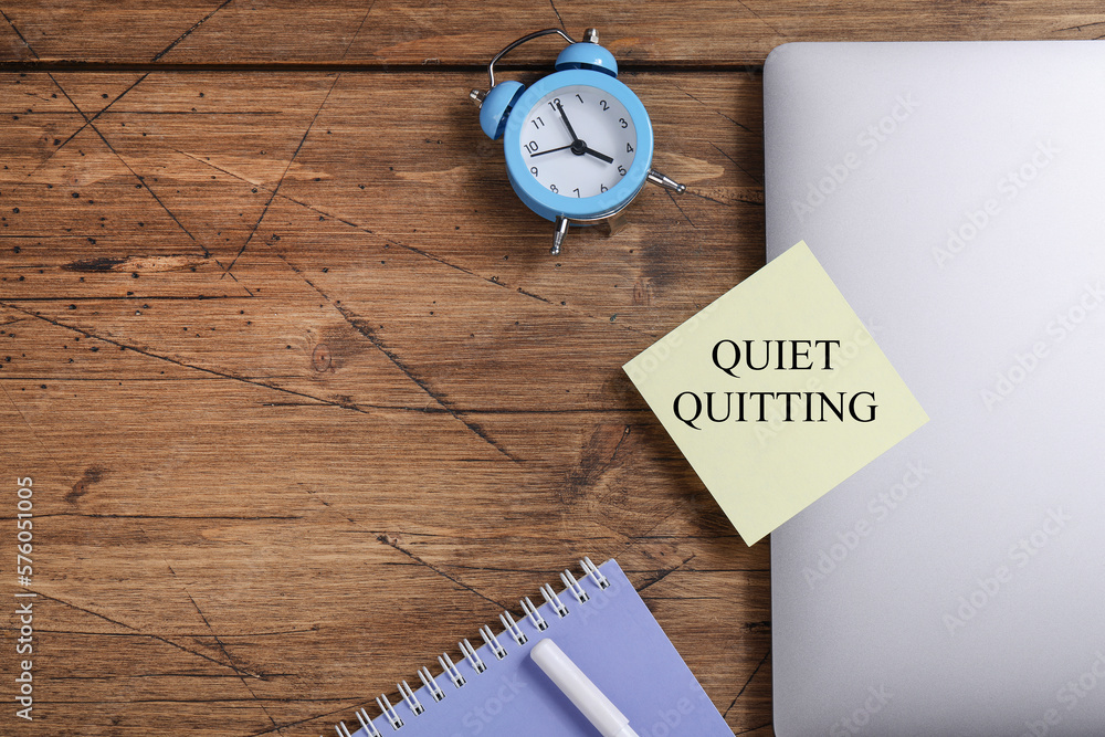 quote 'Quiet quitting' on yellow sticker on computer with clock and notebook. work life balance concept. post covid life philosophy. quote 'Quiet quitting' on yellow sticker on computer with clock and notebook. work life balance concept. post covid life philosophy.
