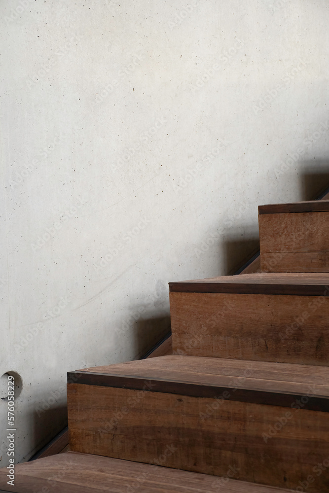 Interior design detail, dark wooden stairs with bare concrete wall.